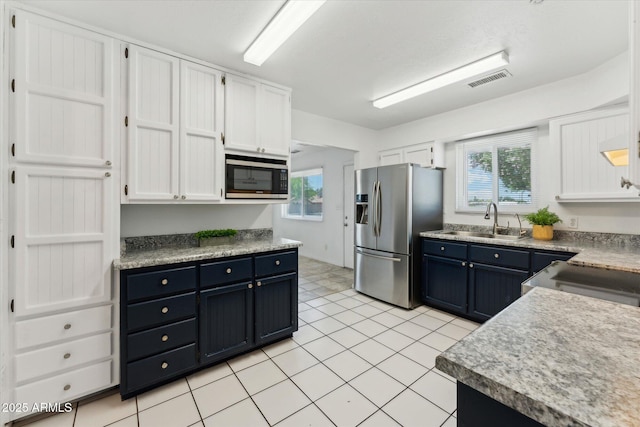 kitchen with stainless steel appliances, a sink, white cabinetry, and healthy amount of natural light