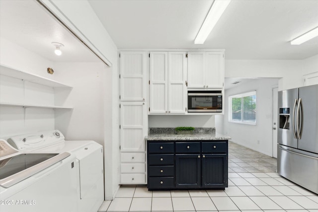 clothes washing area with independent washer and dryer and light tile patterned flooring
