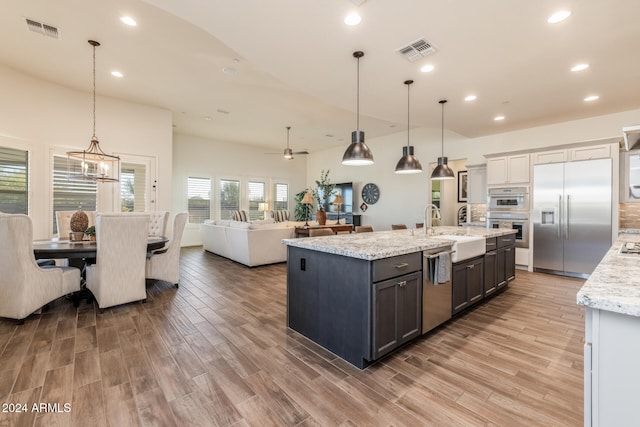 kitchen featuring wood-type flooring, stainless steel appliances, hanging light fixtures, and sink