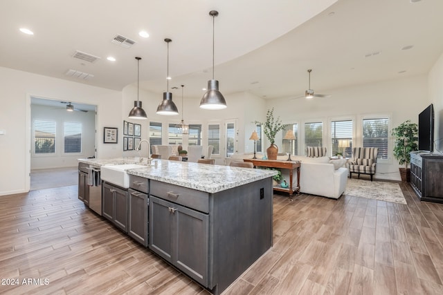 kitchen with light stone countertops, decorative light fixtures, a wealth of natural light, and sink