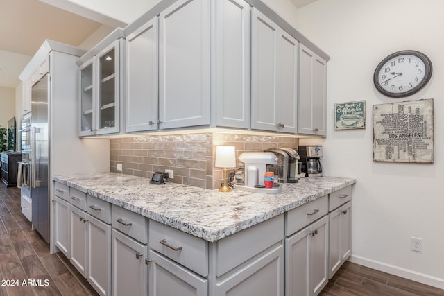 kitchen featuring gray cabinetry, dark hardwood / wood-style floors, light stone countertops, and backsplash