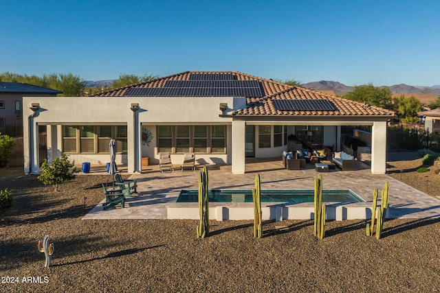 rear view of house featuring solar panels, a patio area, an outdoor living space, and a mountain view