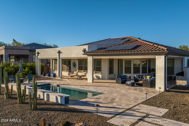 rear view of property featuring solar panels, an outdoor living space, and a patio