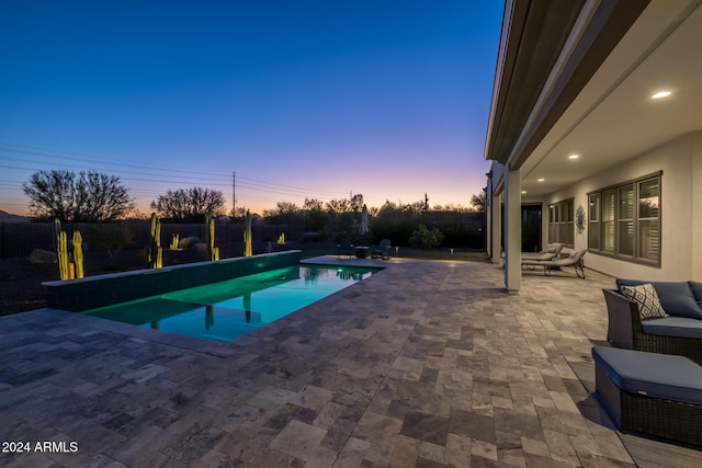 pool at dusk with a patio area