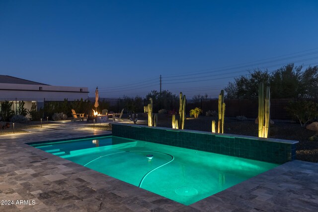 pool at dusk featuring a patio