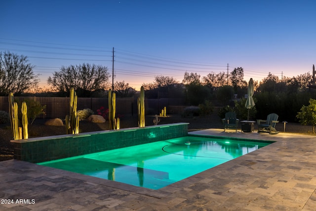 pool at dusk with a patio area