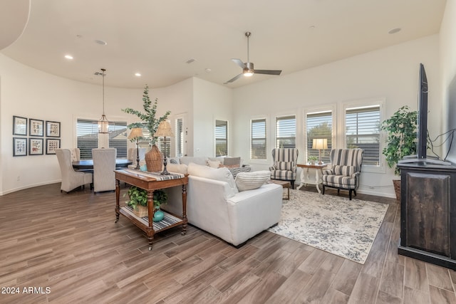 living room with hardwood / wood-style floors, a towering ceiling, and ceiling fan