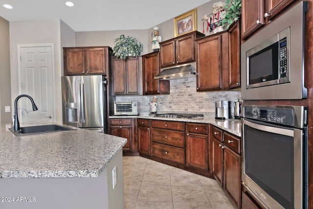 kitchen with appliances with stainless steel finishes, backsplash, dark brown cabinetry, sink, and light tile patterned flooring