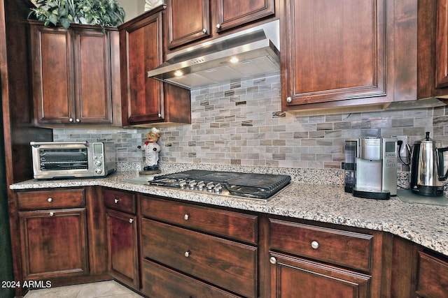 kitchen with light stone countertops, tasteful backsplash, stainless steel gas stovetop, and light tile patterned flooring