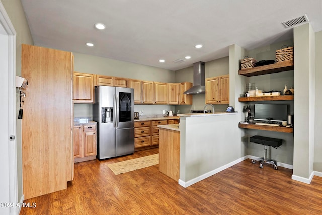 kitchen with wall chimney exhaust hood, stainless steel fridge with ice dispenser, kitchen peninsula, and light hardwood / wood-style flooring