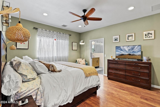 bedroom featuring light hardwood / wood-style flooring, ceiling fan, and ensuite bath