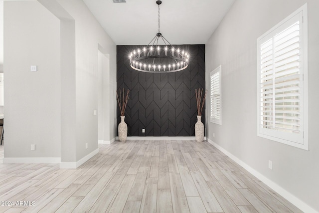 spare room featuring light hardwood / wood-style floors and an inviting chandelier