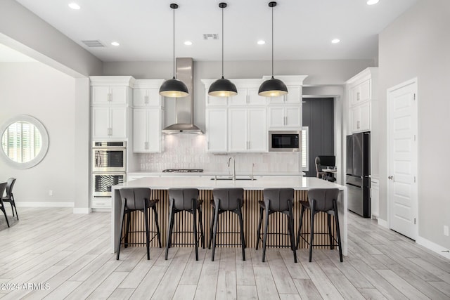 kitchen with stainless steel appliances, decorative light fixtures, sink, and a kitchen island with sink