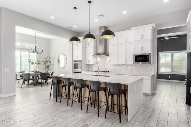 kitchen featuring white cabinets, a spacious island, backsplash, hanging light fixtures, and built in microwave