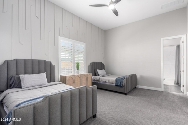 bedroom featuring ensuite bathroom, wood walls, ceiling fan, and carpet flooring