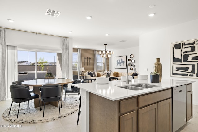 kitchen with pendant lighting, dishwasher, a center island with sink, a notable chandelier, and light tile patterned flooring