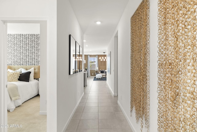 hall with light tile patterned floors and an inviting chandelier