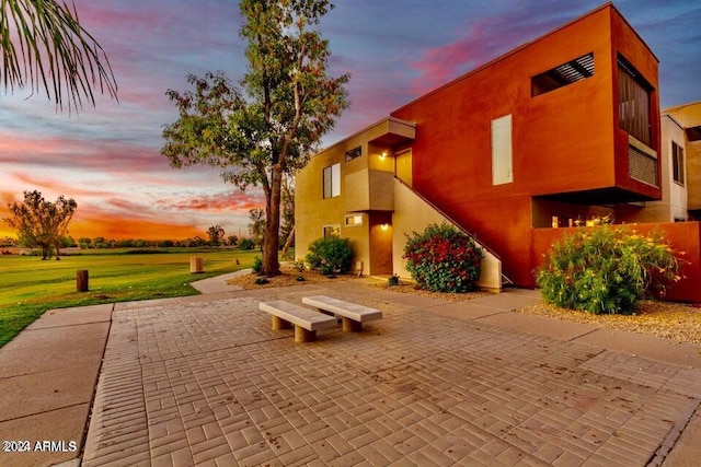 patio terrace at dusk featuring a yard