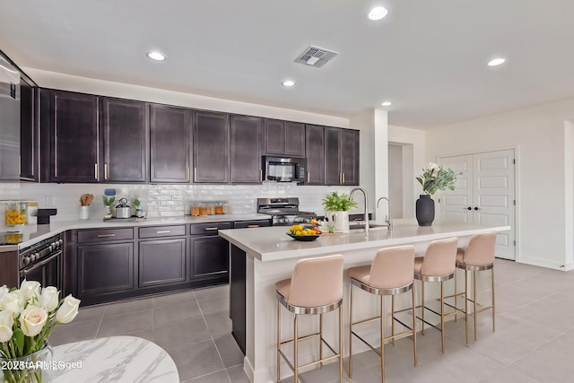 22876 E Via Del Sol, Queen Creek, AZ 85142 - kitchen featuring black microwave, range with gas cooktop, a breakfast bar area, tasteful backsplash, and light tile patterned floors