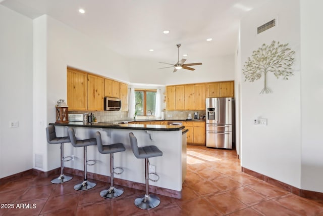 kitchen with a high ceiling, stainless steel appliances, backsplash, and kitchen peninsula