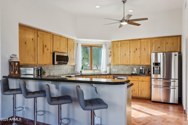 kitchen featuring tasteful backsplash, kitchen peninsula, a towering ceiling, sink, and appliances with stainless steel finishes