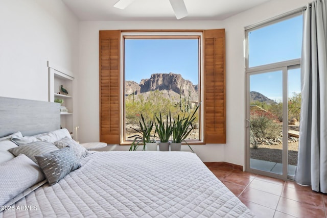 tiled bedroom featuring ceiling fan, access to outside, and a mountain view