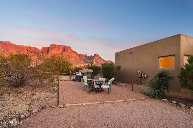 patio terrace at dusk featuring a mountain view and grilling area