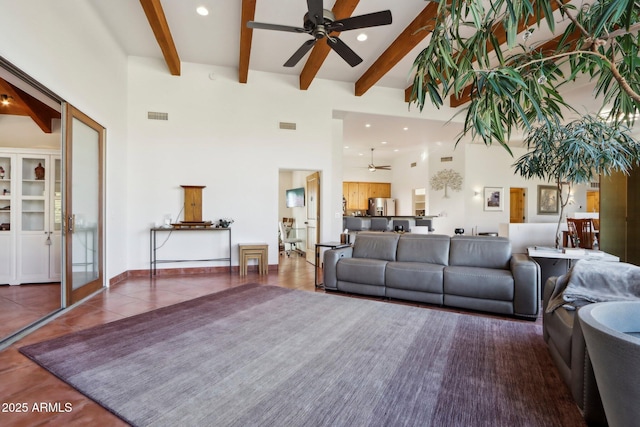 tiled living room with beam ceiling, ceiling fan, and a towering ceiling