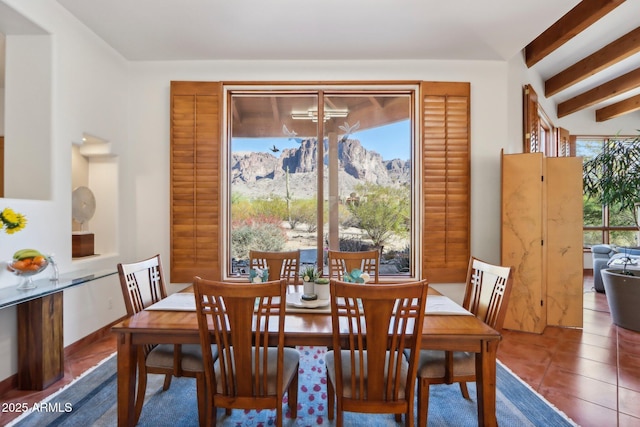 dining area featuring a wealth of natural light, beam ceiling, tile patterned floors, and a mountain view