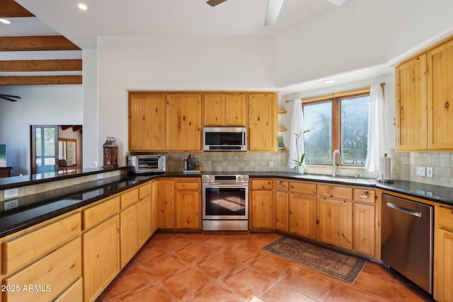 kitchen featuring light tile patterned floors, appliances with stainless steel finishes, tasteful backsplash, dark stone counters, and sink