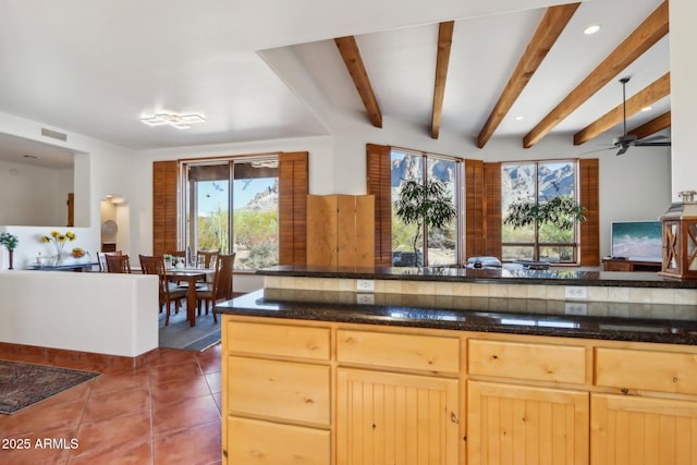 kitchen featuring light brown cabinetry, dark tile patterned floors, dark stone counters, and ceiling fan