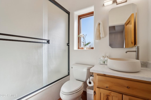 full bathroom featuring toilet, vanity, and shower / bath combination with glass door