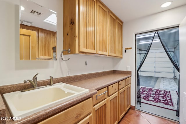 kitchen with light brown cabinetry, sink, and light tile patterned flooring