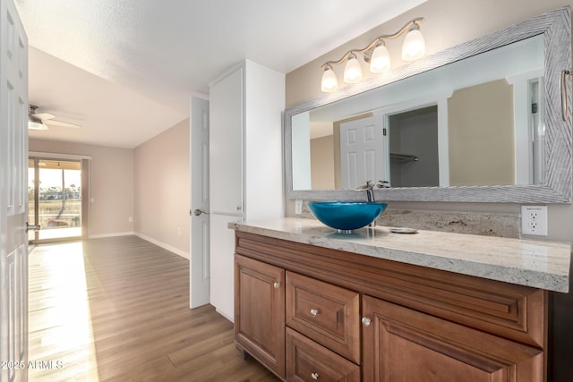 bathroom with a ceiling fan, baseboards, wood finished floors, and vanity