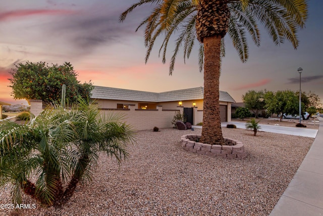 mid-century modern home with driveway, fence, an attached garage, and stucco siding