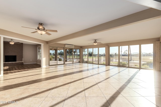 unfurnished living room featuring light tile patterned floors, ceiling fan, a wall unit AC, baseboards, and a brick fireplace