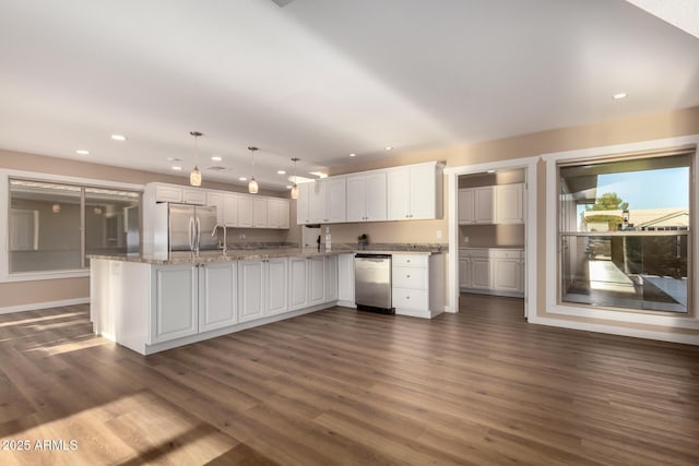 kitchen with dark wood-style floors, stainless steel appliances, decorative light fixtures, and white cabinets