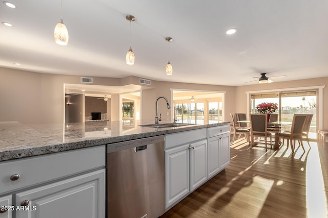 kitchen with dishwasher, light stone counters, hanging light fixtures, white cabinetry, and a sink