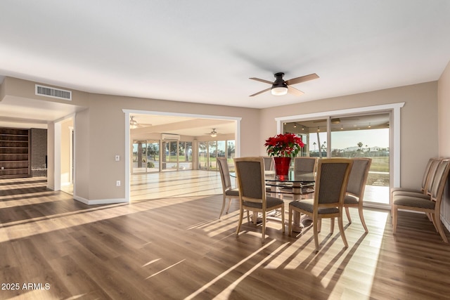 dining room featuring a ceiling fan, visible vents, baseboards, and wood finished floors