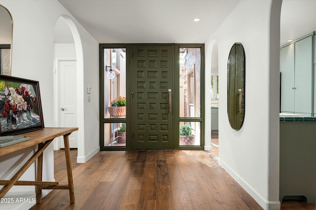 entryway featuring baseboards, arched walkways, hardwood / wood-style floors, and recessed lighting