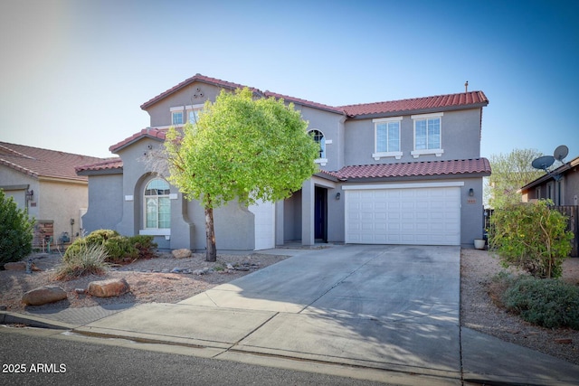 mediterranean / spanish-style home featuring an attached garage, a tiled roof, concrete driveway, and stucco siding