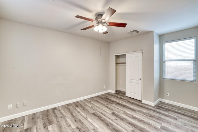 unfurnished bedroom featuring a closet, visible vents, ceiling fan, wood finished floors, and baseboards