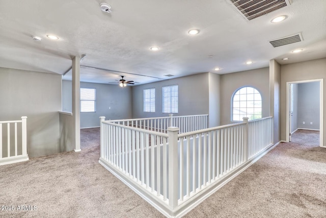 hall featuring carpet floors, a wealth of natural light, and visible vents