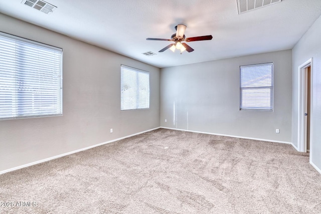 empty room featuring carpet floors, visible vents, and a ceiling fan