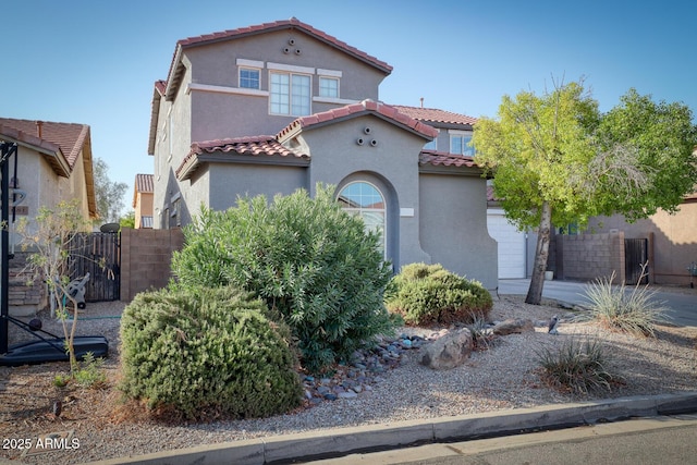 mediterranean / spanish-style home with a gate, fence, a tiled roof, and stucco siding