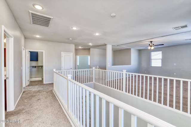 corridor featuring light carpet, baseboards, visible vents, and recessed lighting