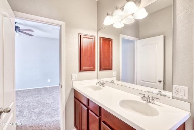 bathroom featuring double vanity, a sink, a ceiling fan, and baseboards