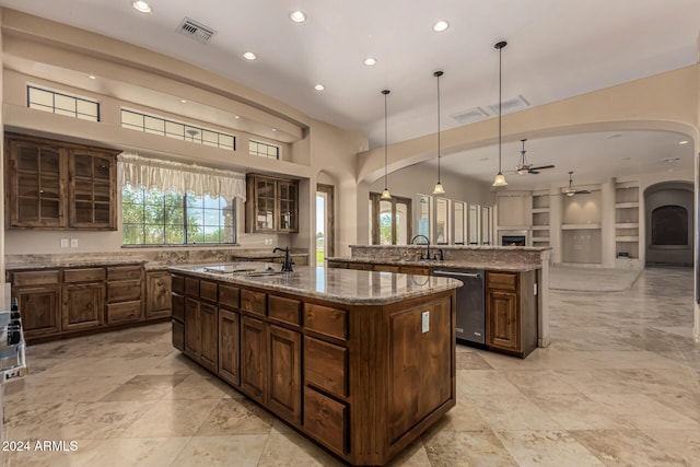 kitchen with dishwasher, an island with sink, decorative light fixtures, and built in shelves