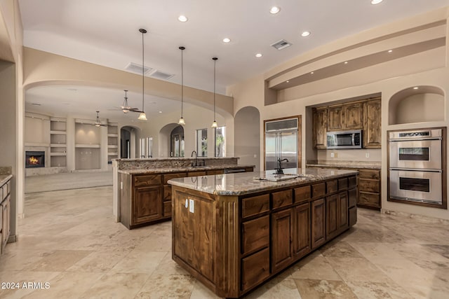 kitchen featuring a spacious island, hanging light fixtures, sink, appliances with stainless steel finishes, and built in shelves