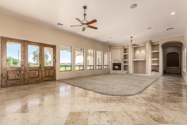 unfurnished living room featuring built in features and ceiling fan